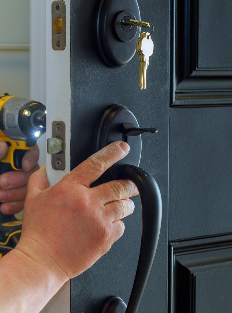 closeup of a professional locksmith installing a new lock on a house exterior door with the inside